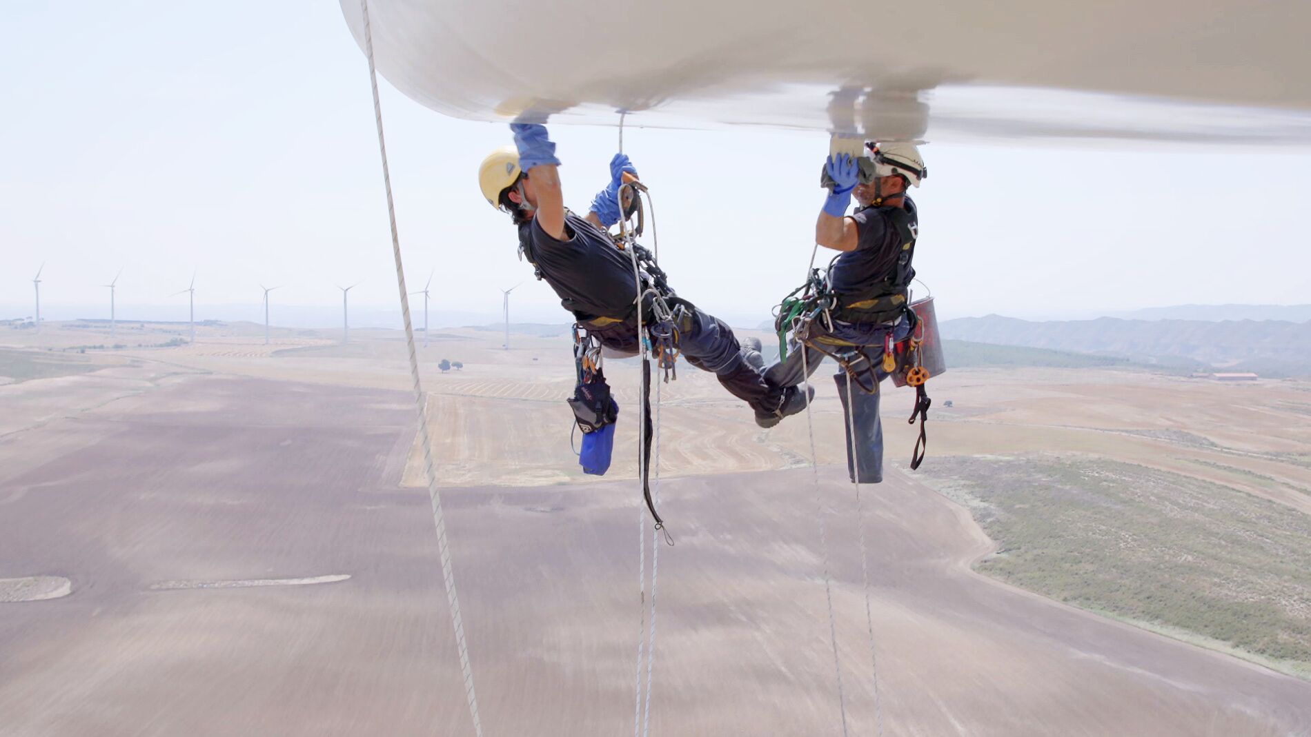 Colgados a 80 metros de altura para limpiar un molino de viento